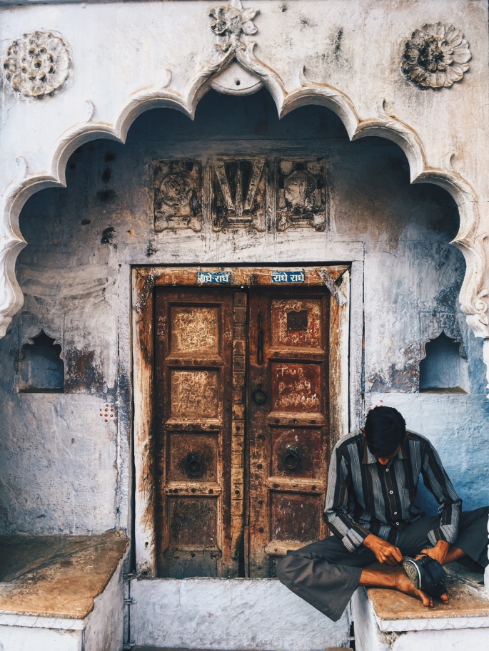 A traditional old door, with a man resting next to it.