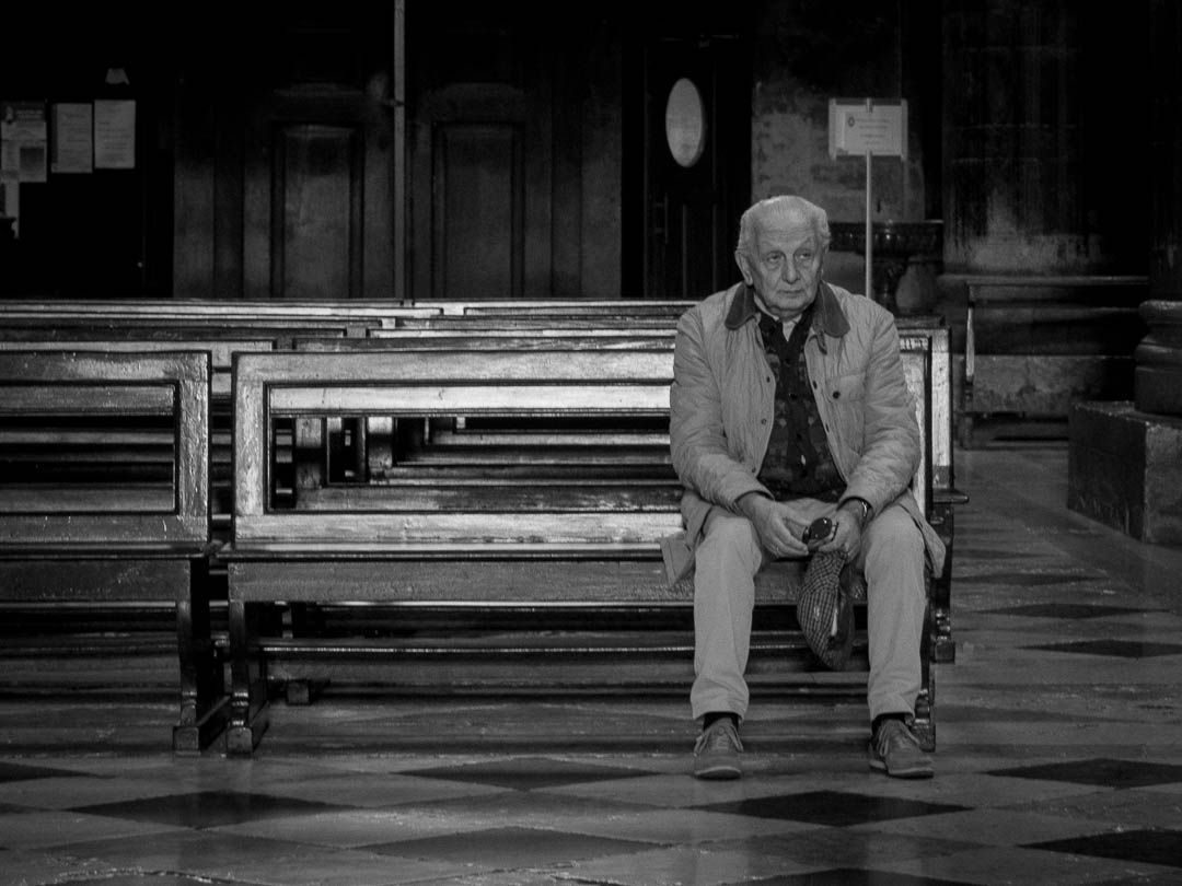 A man sits alone in a church in Cremona, Italy